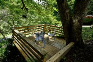 a bench sitting on a wooden deck next to a tree at Charming Appalachian Mountain Cabin for Glamping near the Nantahala River in Aquone