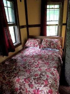 a bed in a bedroom with two windows at Tree Top Cabin in Crumpler, North Carolina in Crumpler