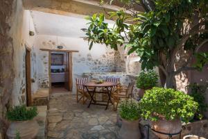 a patio with a table and chairs and trees at El Greco Traditional Houses in Skhinokápsala