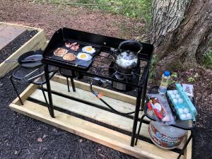 a grill on a wooden table with food on it at Luxurious Safari Tent in Cooperstown, NY - Perfect Glamping Spot for a Romantic Getaway in Cooperstown
