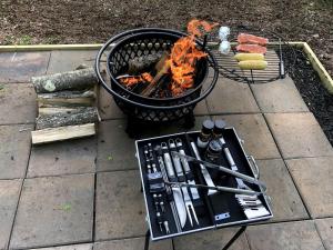 a grill with tongs next to a grill with food at Luxurious Safari Tent in Cooperstown, NY - Perfect Glamping Spot for a Romantic Getaway in Cooperstown