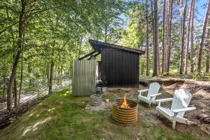 a small cabin with two chairs and a fire pit at Secluded Modern Tiny House with Wood-Fired Hot Tub Near Trails in Sears, Michigan in Sears