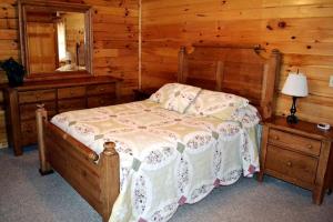 ein Schlafzimmer mit einem Bett in einer Blockhütte in der Unterkunft Log Cabin Rental with Hot Tub near Hocking Hills State Park in Ohio in Cedar Grove