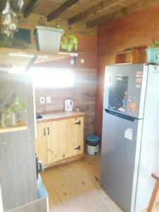 a kitchen with a stainless steel refrigerator and wooden floors at Hermosa Cabaña romantica, bosque, lago y mar in El Pinar
