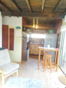 a living room with a table and a kitchen at Hermosa Cabaña romantica, bosque, lago y mar in El Pinar