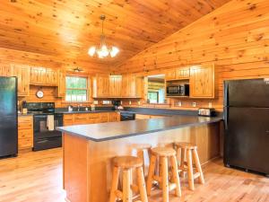 eine Küche mit Holzschränken und eine große Insel mit Barhockern in der Unterkunft Gorgeous and Spacious Cabin Rental for a Group Vacation near Hocking Hills State Park, Ohio in Cedar Grove