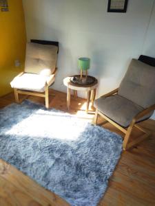 a living room with two chairs and a blue rug at Hermosa Cabaña romantica, bosque, lago y mar in El Pinar
