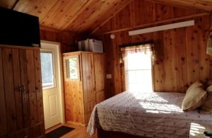 a bedroom with a bed in a wooden room at Simple Weekend Getaway near the Black Hills Region of South Dakota in Sundance