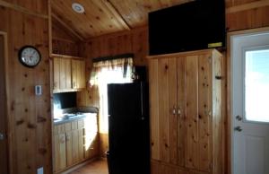 a kitchen with a refrigerator and a clock on the wall at Simple Weekend Getaway near the Black Hills Region of South Dakota in Sundance