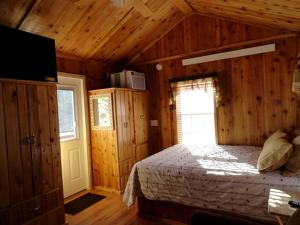 a bedroom with a bed in a wooden room at Simple Weekend Getaway near the Black Hills Region of South Dakota in Sundance