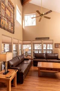 a living room with a leather couch and a ceiling fan at Beautiful Secluded Cabin with a Hot Tub near Monarch Mountain in Colorado in Monarch