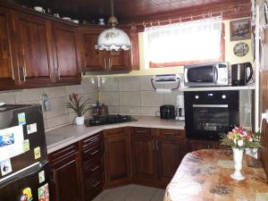 a kitchen with wooden cabinets and a black refrigerator at Tiszavirág Vendégház in Abádszalók