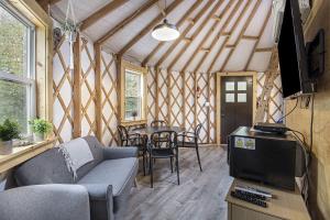 a living room with a couch and a tv and a table at Secluded Off-Grid Yurt with Forest Views Near Trails in Sears, Michigan in Sears