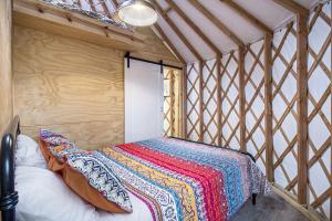 a bed with a colorful blanket in a room at Secluded Off-Grid Yurt with Forest Views Near Trails in Sears, Michigan in Sears