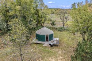 a green tent in the middle of a field at Secluded Off-Grid Yurt with Forest Views Near Trails in Sears, Michigan in Sears