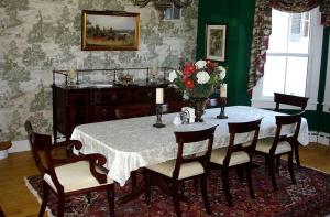 a dining room table with chairs and a vase of flowers at 1856 Manor Vacation Rental on Huge Horse and Cattle Farm near Charlottesville, Virginia in Gordonsville