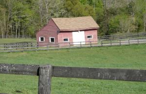 a red barn in a field next to a fence at 1856 Manor Vacation Rental on Huge Horse and Cattle Farm near Charlottesville, Virginia in Gordonsville +8 photos