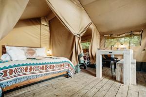 a bedroom in a tent with a bed and a desk at Delightful Safari Tent with Fire Pit and Sauna in North Woodstock, New Hampshire in Woodstock