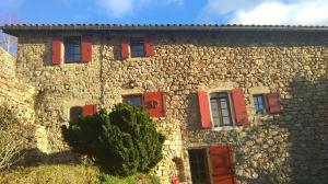 um edifício de pedra com persianas vermelhas em Gîte Laboule pour 4 personnes em Laboule