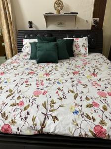 a large bed with a floral comforter on it at Nani s House - Warmth & Comfort in Dehradun