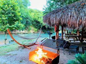 a hammock and a fire pit next to a river at Dreamy Oasis on the San Marcos River: Luxurious Safari Tent Perfect for Glamping near Kingsbury, Texas in Staples
