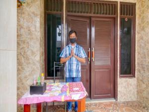a man standing in front of a table wearing a mask at Hotel O Nakula Sadewa in Areman