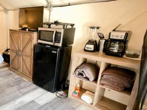 a small kitchen with a microwave and a refrigerator at Charming Safari Tent on the San Marcos River near Kingsbury, Texas - Perfect for an Aquatic Adventure in Staples +42 photos