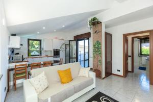 Una sala de estar con un sofá blanco y una cocina. en Dai Gheller Villa luminosa con piscina vicino Como e Milano, en Carbonate