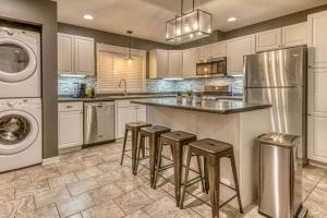 a kitchen with a refrigerator and bar with stools at Incredible Cozy Cottage with Hot-tub in Gary, Indiana in Miller