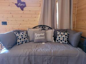 a gray couch with pillows and a sign on it at Lovely Nature Getaways near Austin, Texas, in this Cute Cabin Rental in Pipe Creek in Pipe Creek