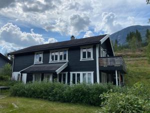 una casa negra con ventanas blancas en un campo en 2 mannsbolig i Hemsedal sentrum - 3 soverom og 7 sengeplasser, en Hemsedal