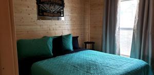 a bedroom with a bed with a blue comforter and a window at Lovely Nature Getaways near Austin, Texas, in this Cute Cabin Rental in Pipe Creek in Pipe Creek