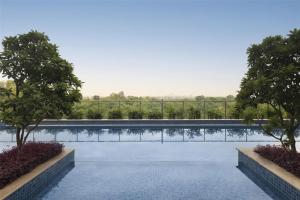 a swimming pool with trees and a fence at Radisson Hotel Delhi MG Road in New Delhi
