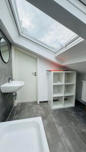 a bathroom with a white sink and a skylight at Charming Attic Retreat with Sloped Roof in Böblingen