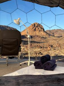 a desk with a lamp and purple towels on a bed at Unique and Pet Friendly Glamping Dome with Views of Big Bend National Park, Perfect for a Texas Glamping Getaway in Terlingua