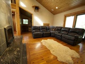 SmithfieldにあるStately and Unique Cabin Rental with a Wood-Burning Stove near Logan, Utahのリビングルーム(黒い革張りのソファ、ラグ付)