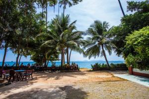 a beach with tables and palm trees and the ocean at House 4 people sea view 100 m from the beach in Klong Muang Beach