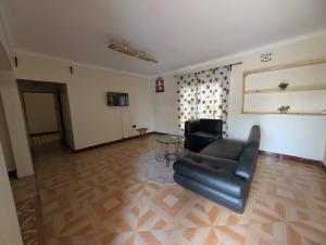 a living room with a black leather couch and a table at Shavia Home in Arusha