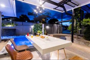a patio with a table and chairs and a pool at Pool Villa Suchada 3 bedrooms max 7 peoples in Ban Khlong Haeng