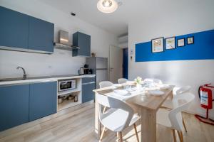 a kitchen and dining room with blue cabinets and a wooden table and chairs at LAKE COMO - 2min to Lake and Station - Free Park and Wifi in Lecco