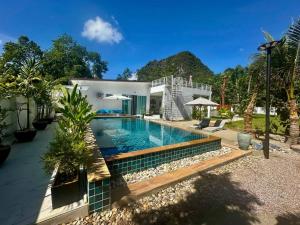 a swimming pool in front of a house at Baan Suan pool valley Villa in Ban Nong Thale