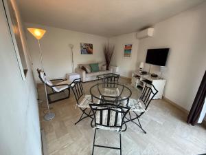 Una sala de estar con una mesa de cristal y sillas. en Beautiful F2 pool in Islette du Riou, en Mandelieu-la-Napoule