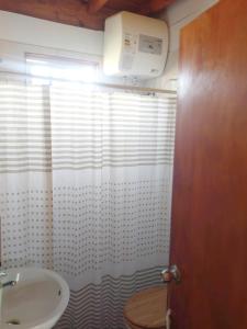 a bathroom with a sink and a white shower curtain at Hermosa Cabaña romantica, bosque, lago y mar in El Pinar