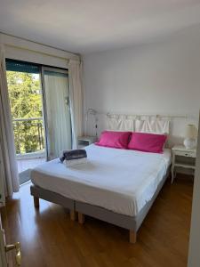 Un dormitorio con una cama grande con almohadas rosas. en Beautiful F2 pool in Islette du Riou, en Mandelieu-la-Napoule