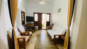 a living room with couches and chairs and a television at Green Island homestay in Kadalundi