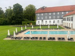 a pool with chairs and umbrellas in front of a building at Premium Penthouse Parkblick in Bad Driburg