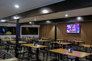 a dining room with tables and chairs and a projection screen at Oasis Newman in Newman