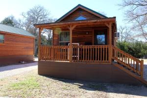 Cabaña de madera con porche y terraza en Pipe Creek Cabin Rental for Glamping Getaways near Austin, Texas, en Pipe Creek