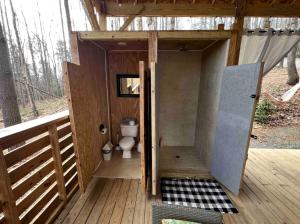 a small bathroom with a toilet on a deck at Magical Glamping Tent in the Woods near Stone Mountain State Park, North Carolina in Traphill
