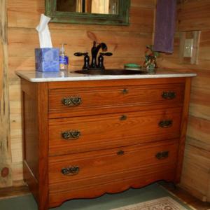 a wooden dresser with a sink in a room at Cozy Cabin Rental with Breakfast Included near Beaumont, Texas in Kountze +2 photos